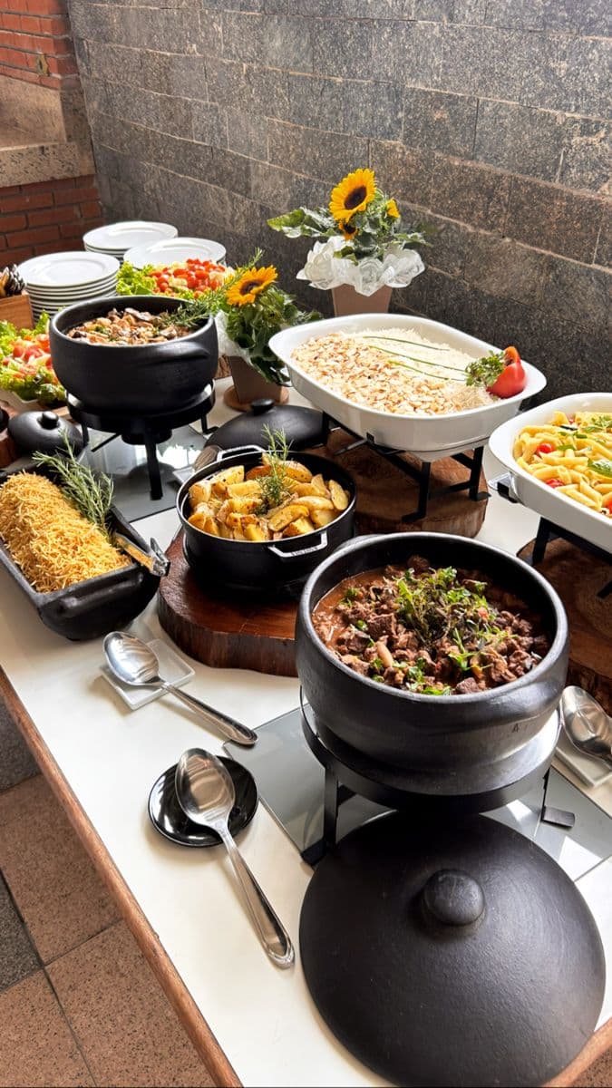 Gourmet buffet spread with meat stew, roasted potatoes, pasta, and rice, decorated with sunflowers.