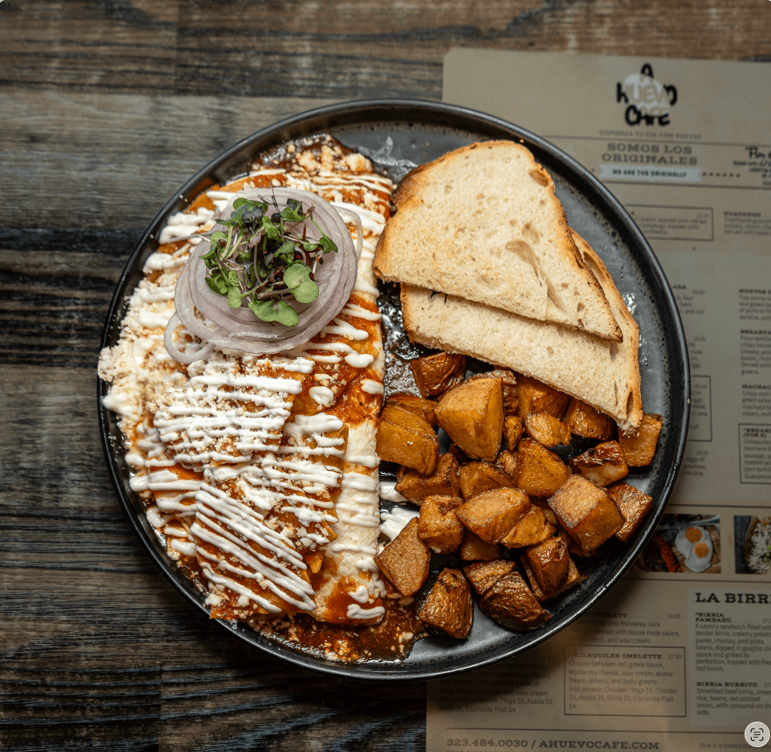 Saucy enchiladas topped with crema and onions, served with roasted potatoes and toasted bread.